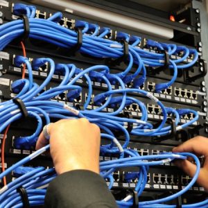 pair of hands wiring an Ethernet patchbay