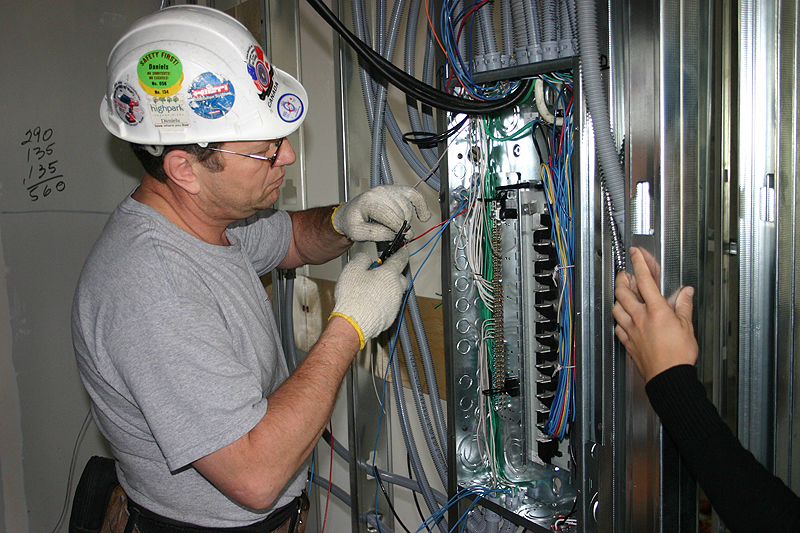 electrical worker connecting wires to fuse panel