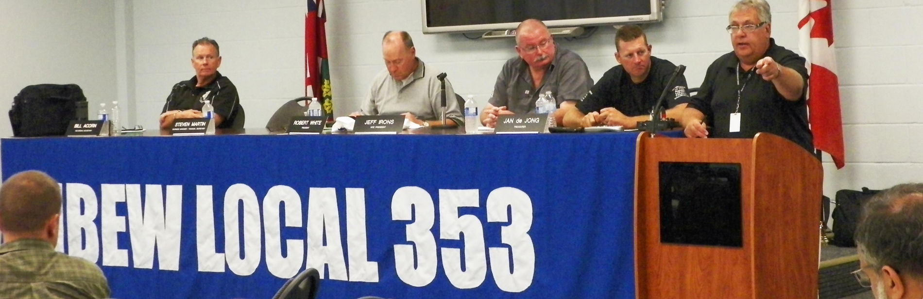 Four IBEW 353 members at a long table and a fifth member at a podium