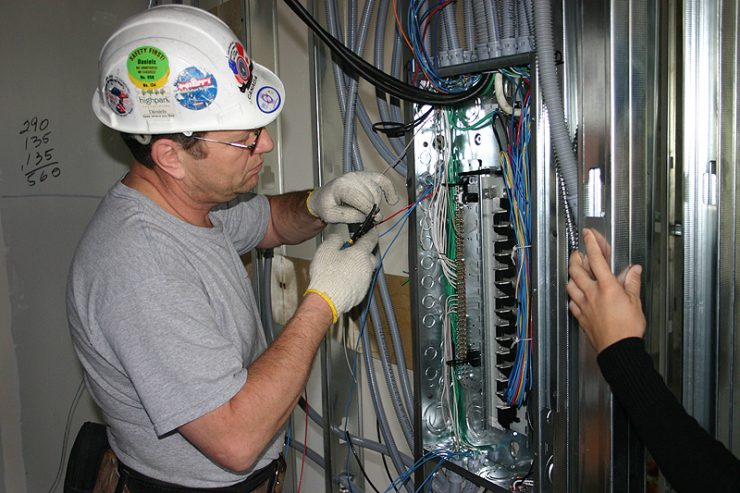 male electrical worker connecting wires to fuse panel