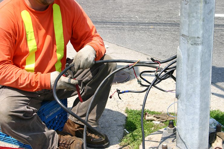 Male electrical worker repairing street signal wiring