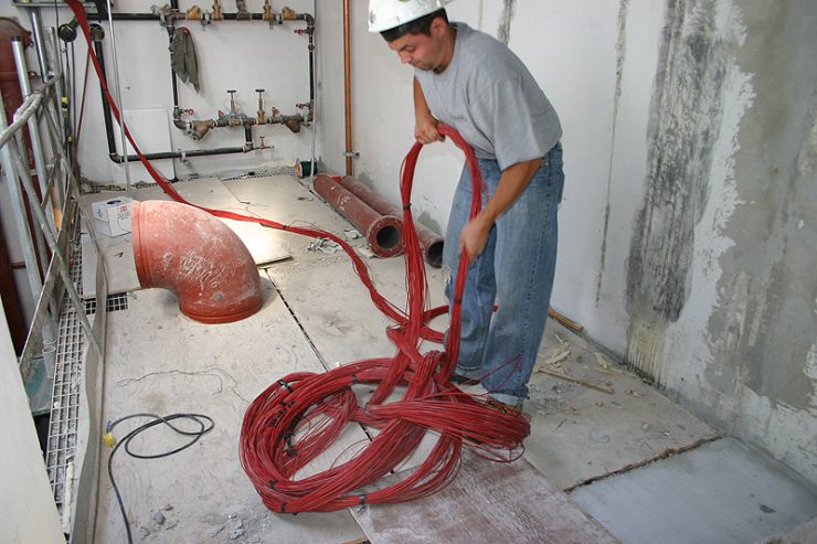 Male electrical worker unraveling electrical wiring