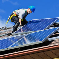worker installing solar panels on a residential house