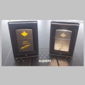 Photo of two Zippo lighters, one matte grey, one silver metal; each has a maple leaf on the lid and the IBEW logo on the case